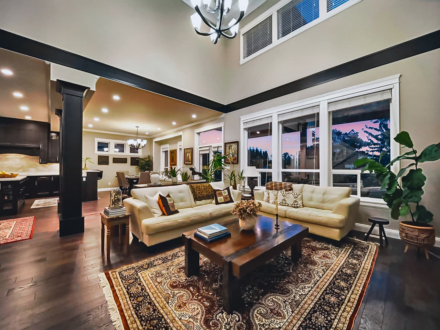 Double-height living room with a fireplace, tall windows and an open staircase