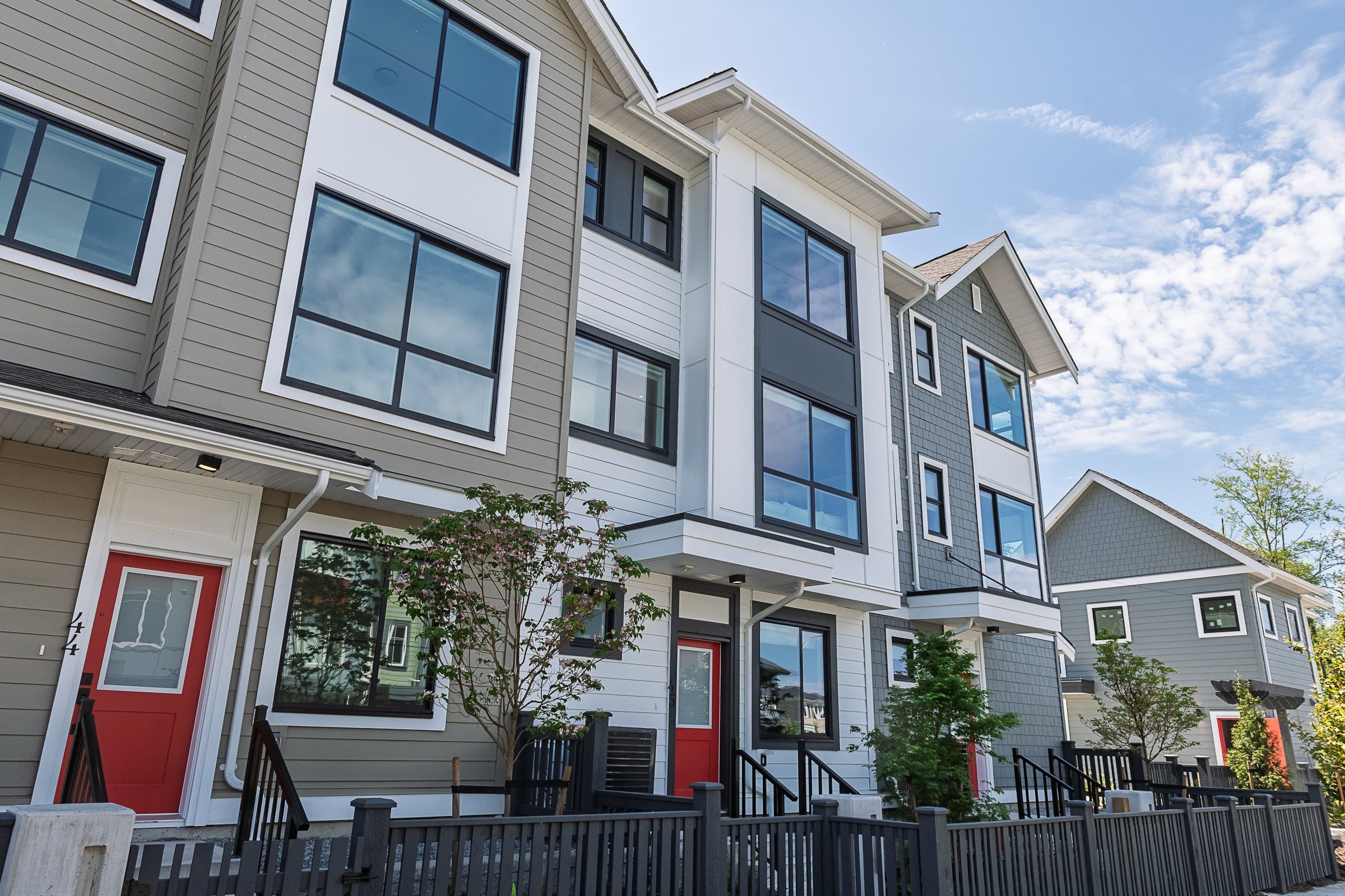 Row of townhomes on a diagonal, with red doors and fences