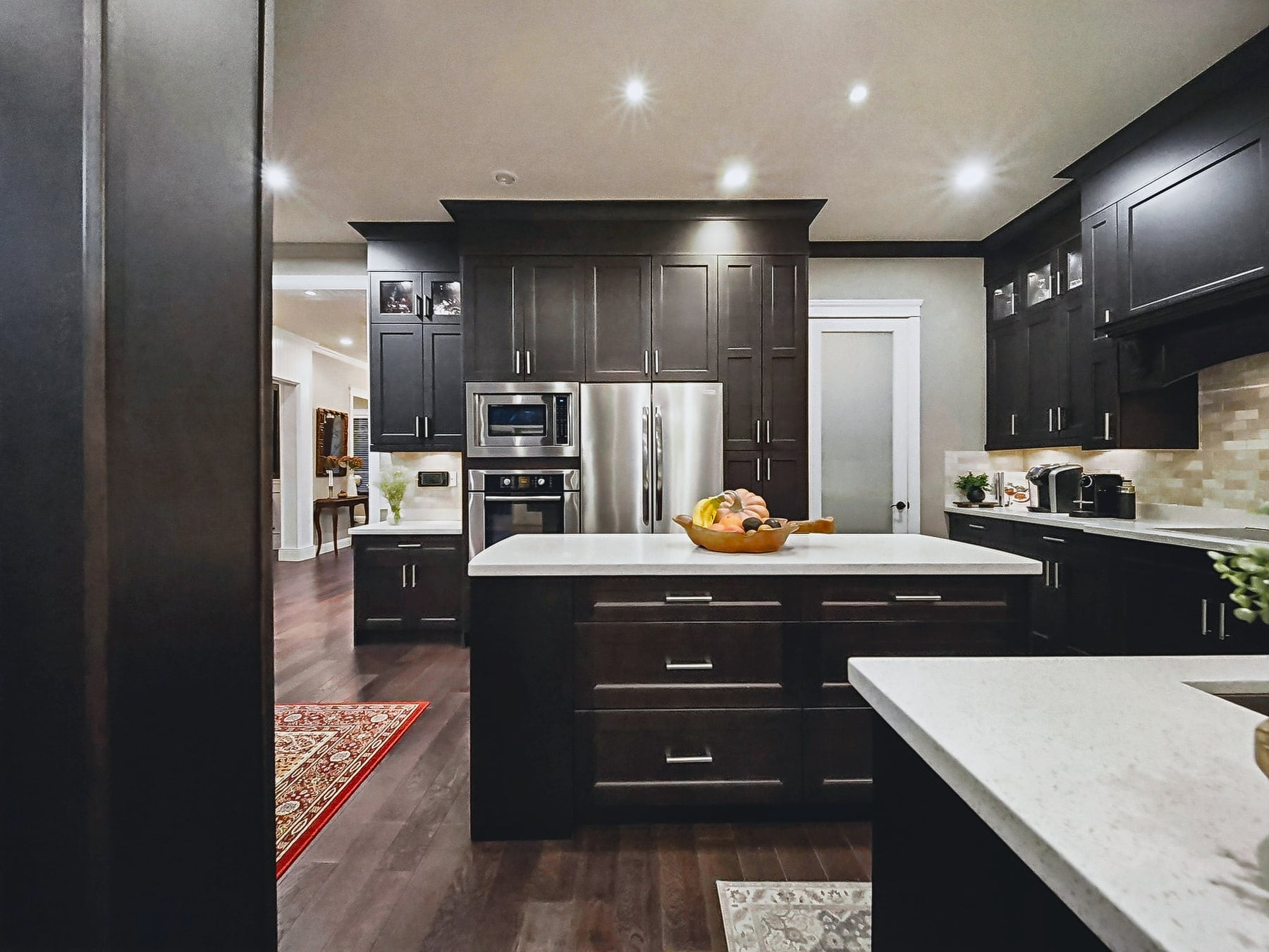 Main kitchen with dark cabinetry, stainless appliances and a light island