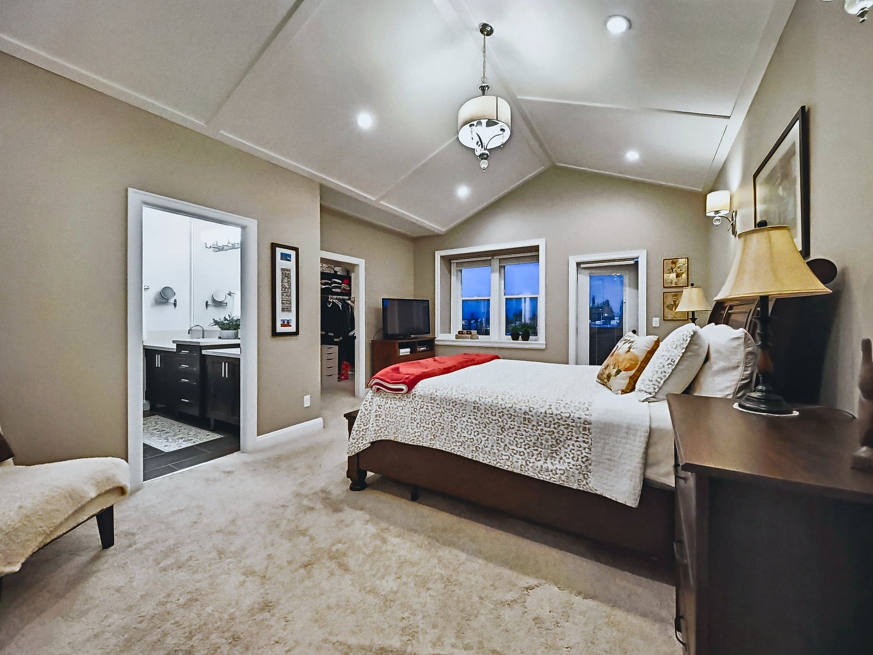 Primary bedroom with a tray ceiling, wide windows and warm neutral finishes