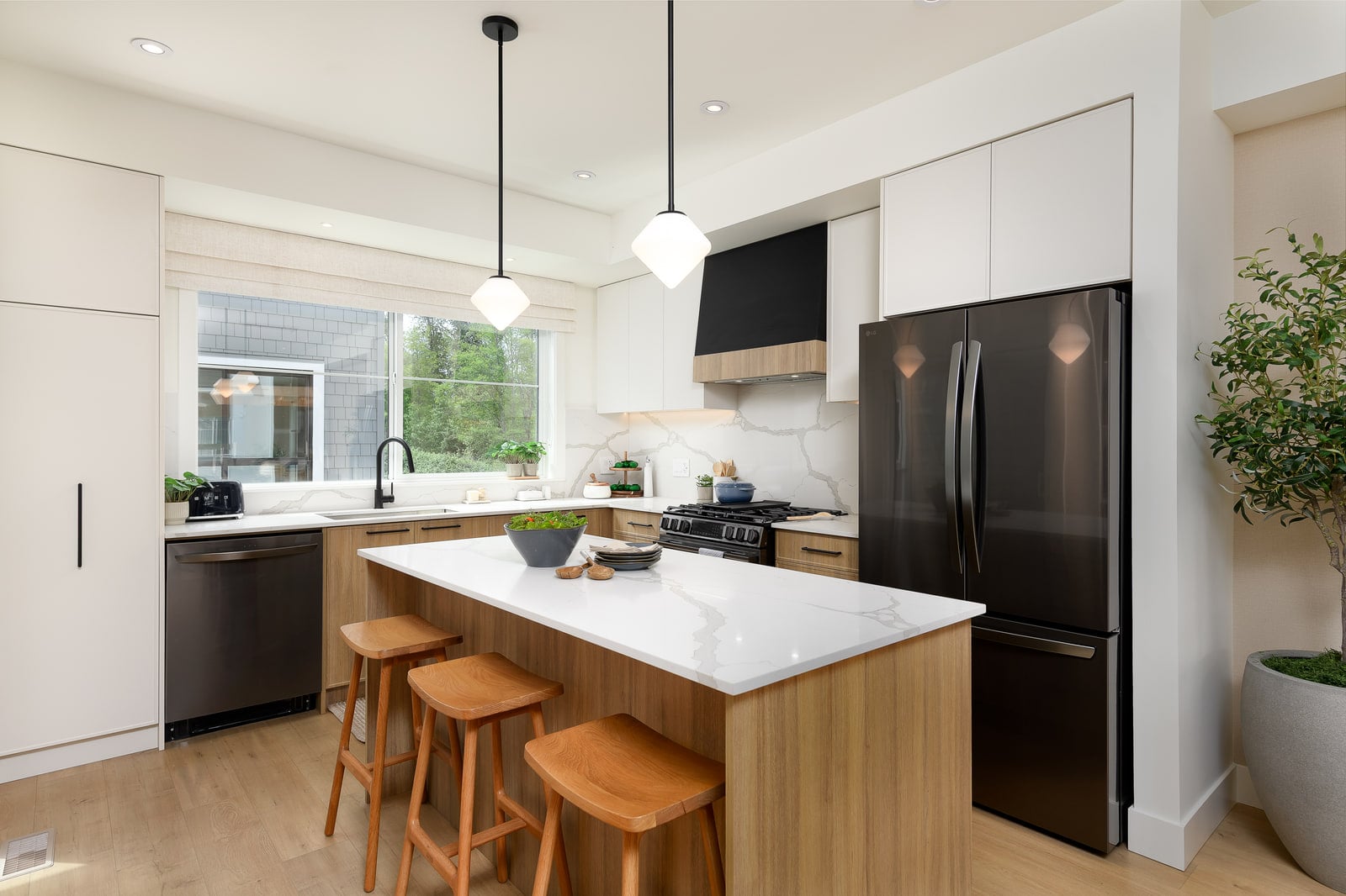 Showhome kitchen with an island, wooden stools, a black French-door fridge and pendant lights