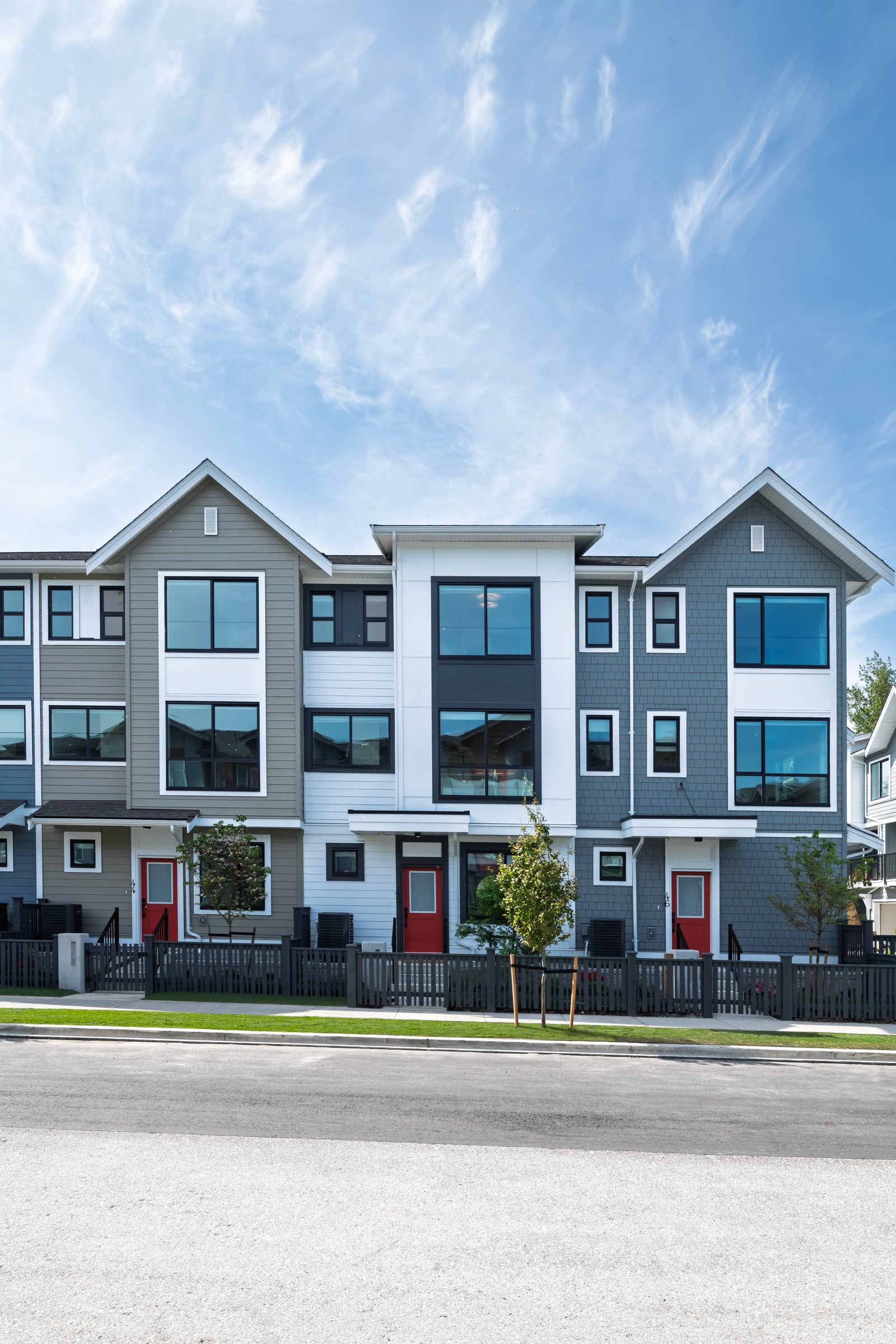 The Silverbrook townhome row seen from the front, with red doors and a clear sky